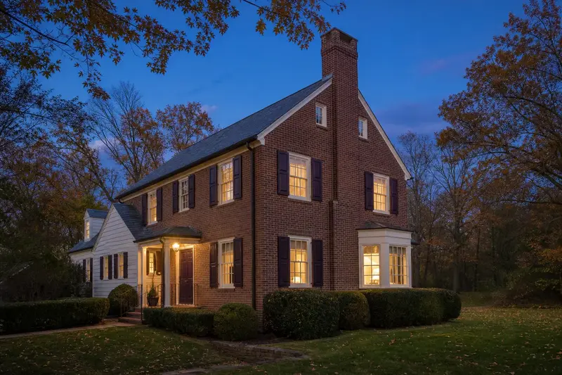 A 1950s Georgian-style brick colonial with an exterior end brick chimney on a gable roof and neat mortar joints; illustrative image