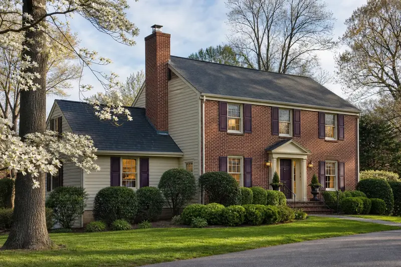 A 1980s brick-front colonial-style suburban house in soft daylight with a red brick chimney with a stainless steel cap and even brickwork; illustrative image