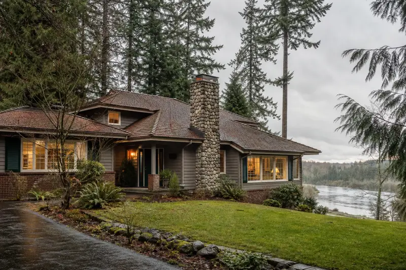 A 1980s Northwest contemporary house with wide eaves with a river rock chimney on a cedar shake roof and neat, even mortar joints; illustrative image