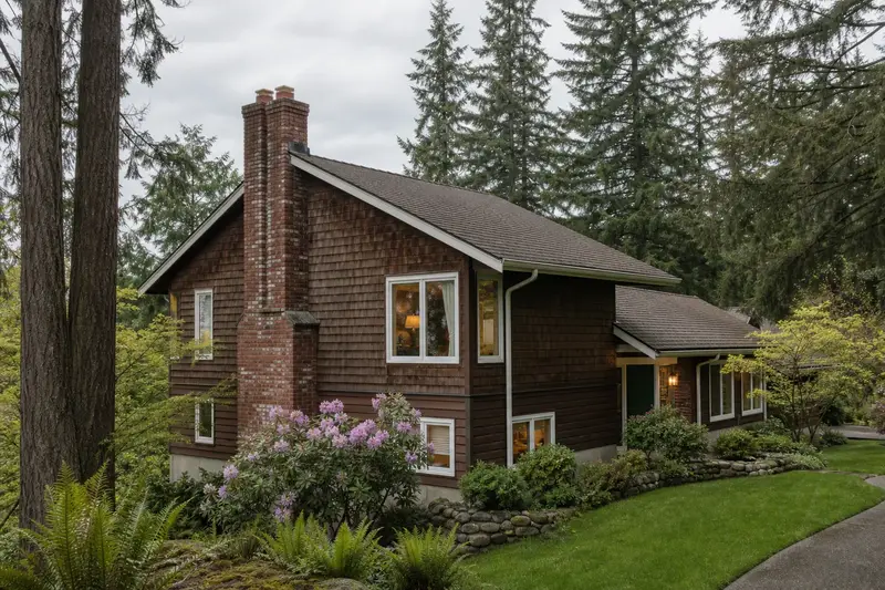 A 1980s cedar-sided split-level house with a two-flue brick chimney on a steep gable roof of clean red brick; illustrative image