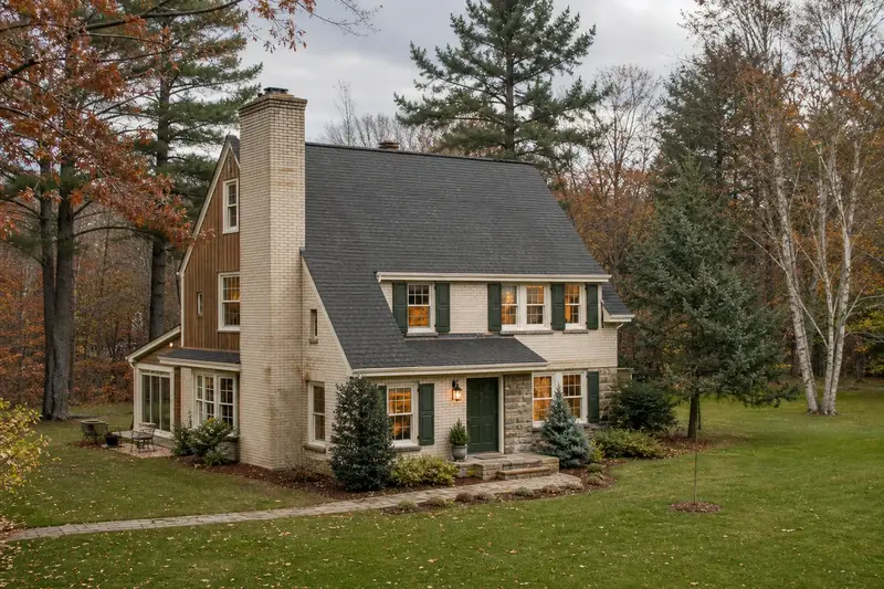 A 1960s two-story suburban house with a tall brick chimney on a steep gable roof and neat, even mortar joints; illustrative image