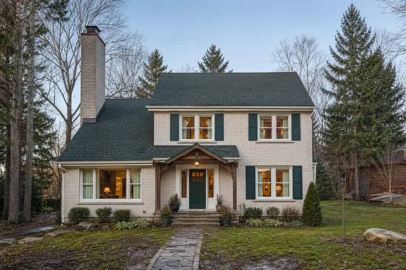 A 1970s two-story suburban house with a tall brick chimney on a steep gable roof and neat mortar joints; illustrative image