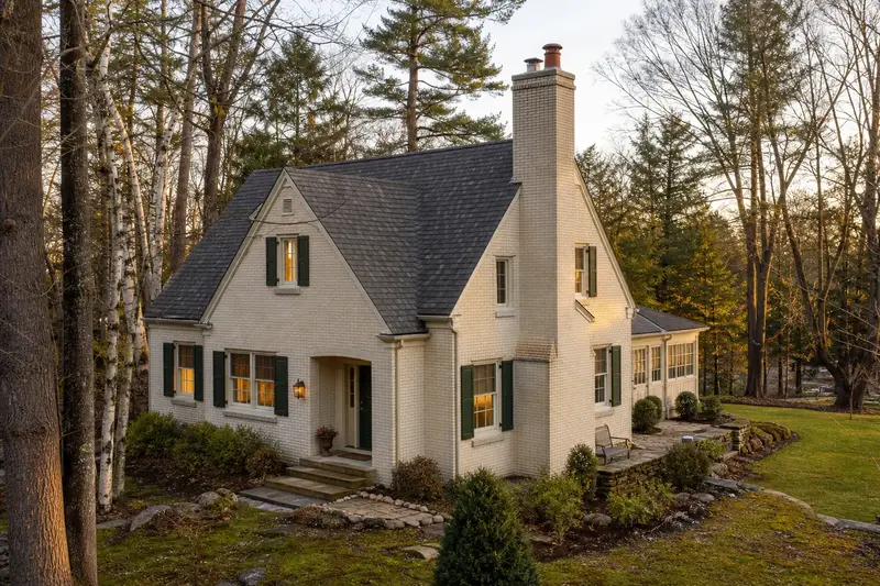 A 1950s pale cream-brick house with a tall brick chimney on a steep gable roof and neat mortar joints; illustrative image