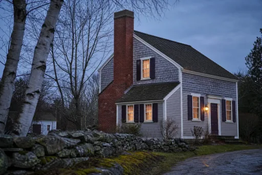 A 1950s saltbox house seen from the street with a red brick chimney with a concrete crown; illustrative image