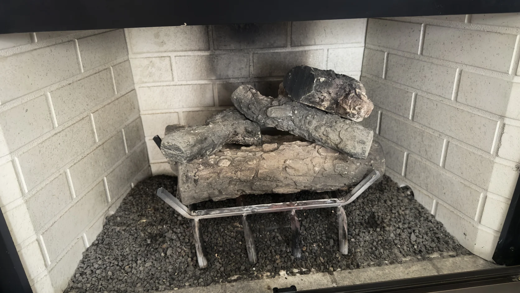 Aged gas log set with soot deposits in a metal firebox