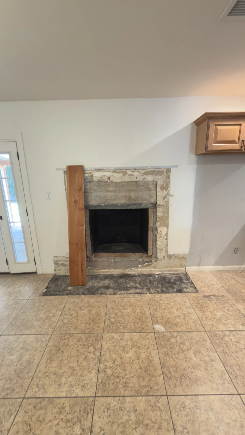 Bare fireplace opening in a tiled room before finishing