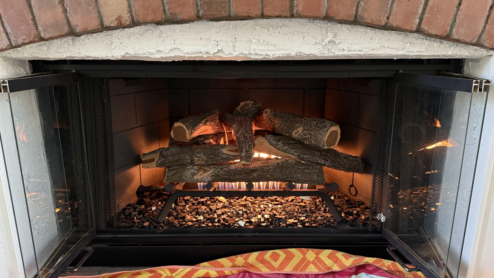 Fire burning in a brick firebox beside a bed