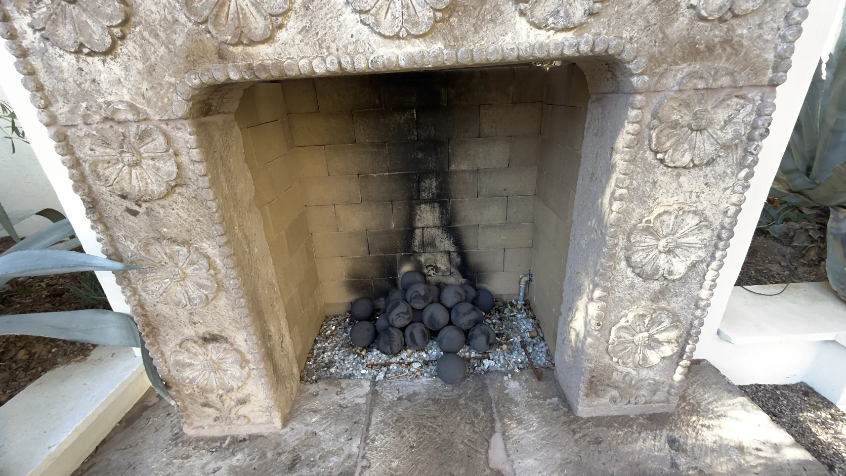 Carved cast-stone fireplace opening with lava rock