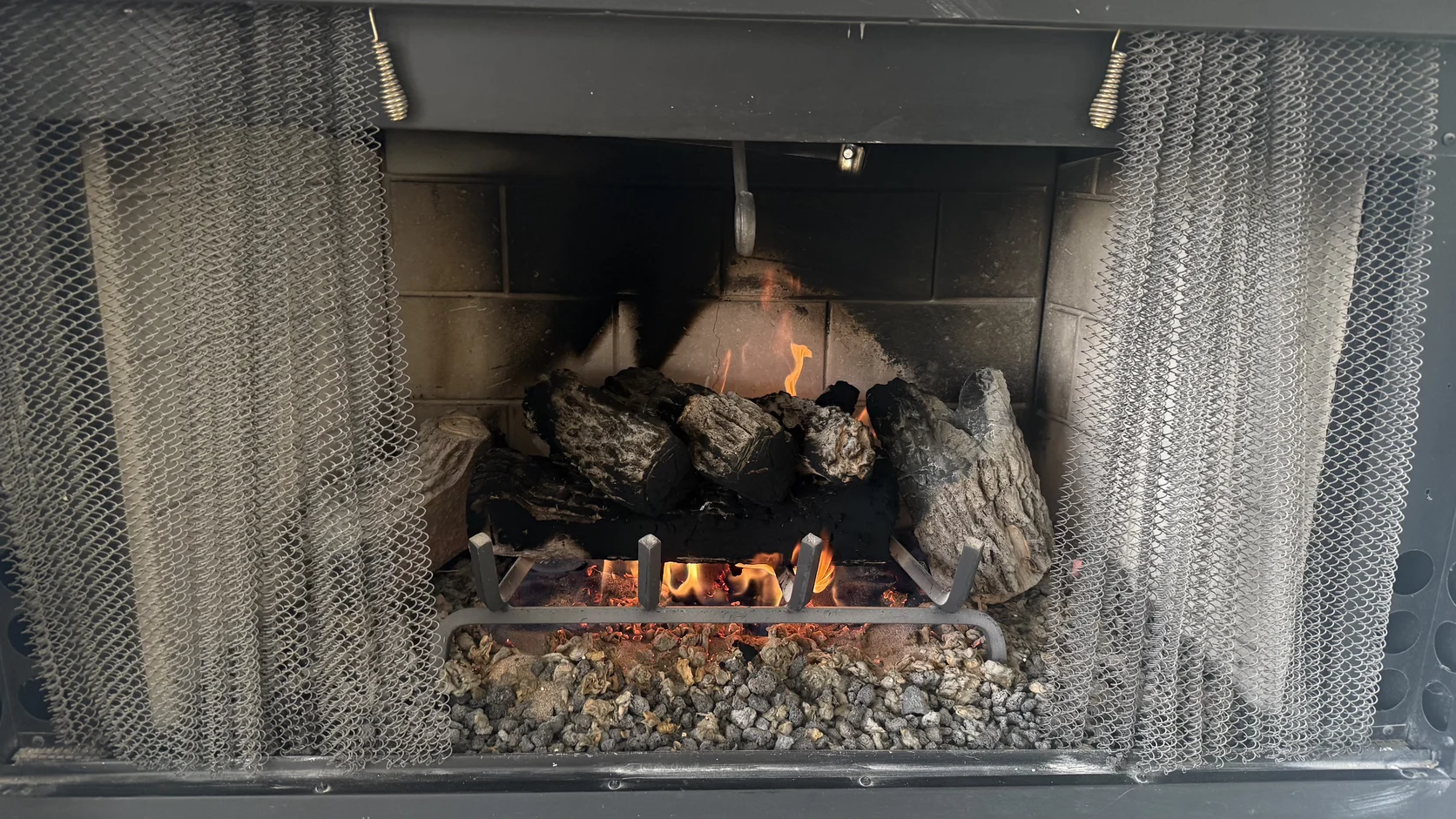 Gas log set behind a mesh fireplace screen