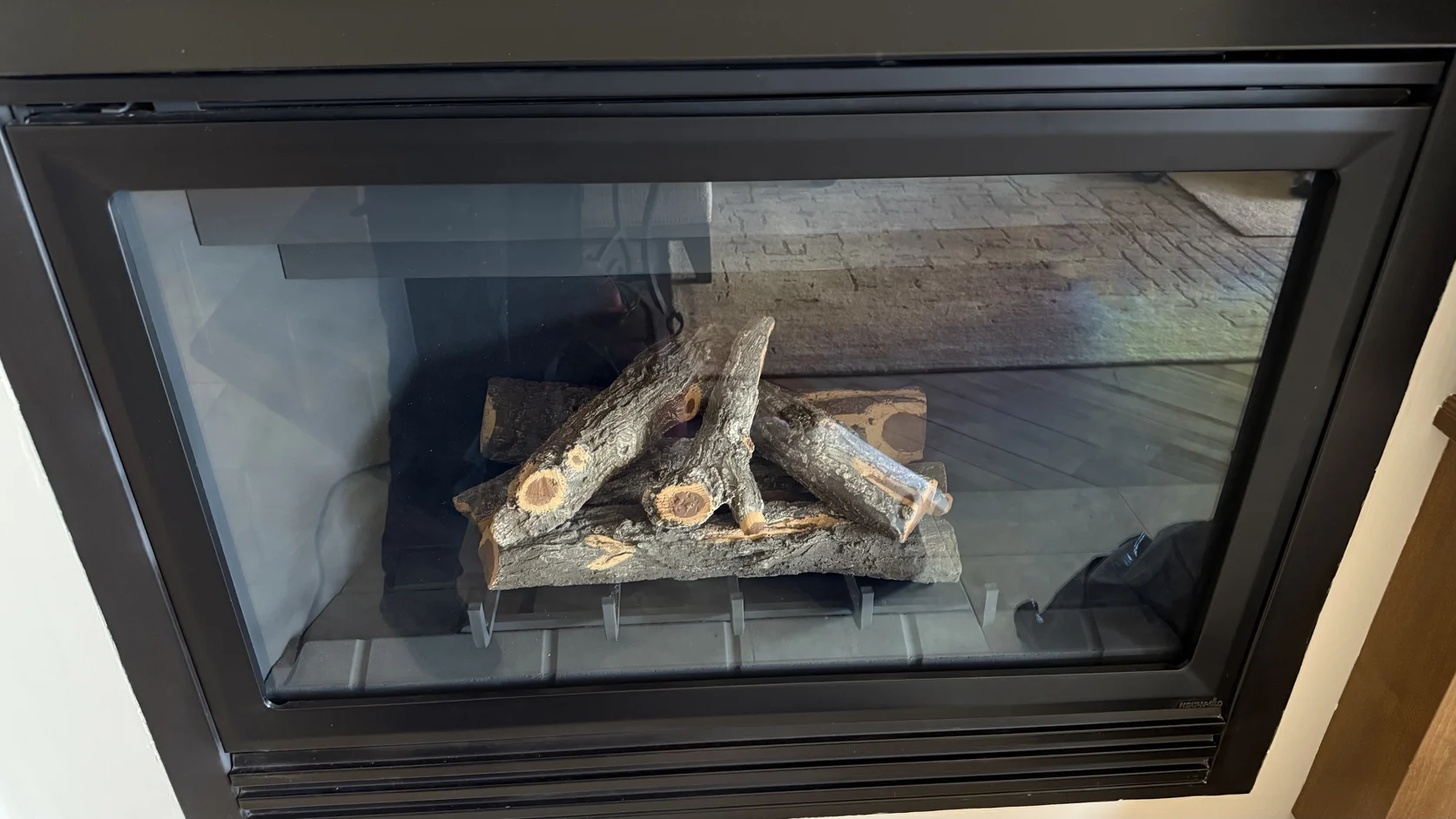 Glass-front fireplace insert with a ceramic log set
