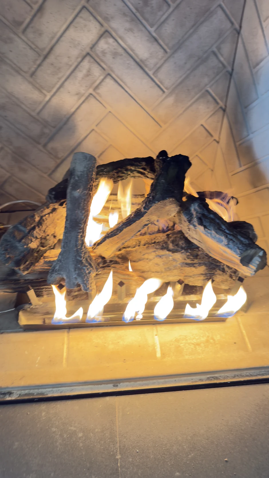 Lit gas logs in a herringbone brick firebox