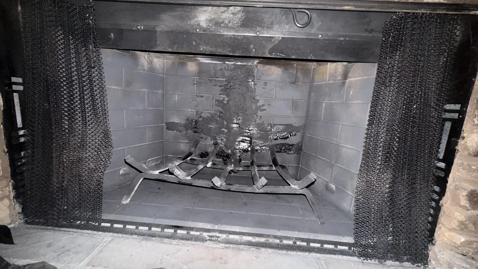 Metal firebox with an empty grate and mesh curtain