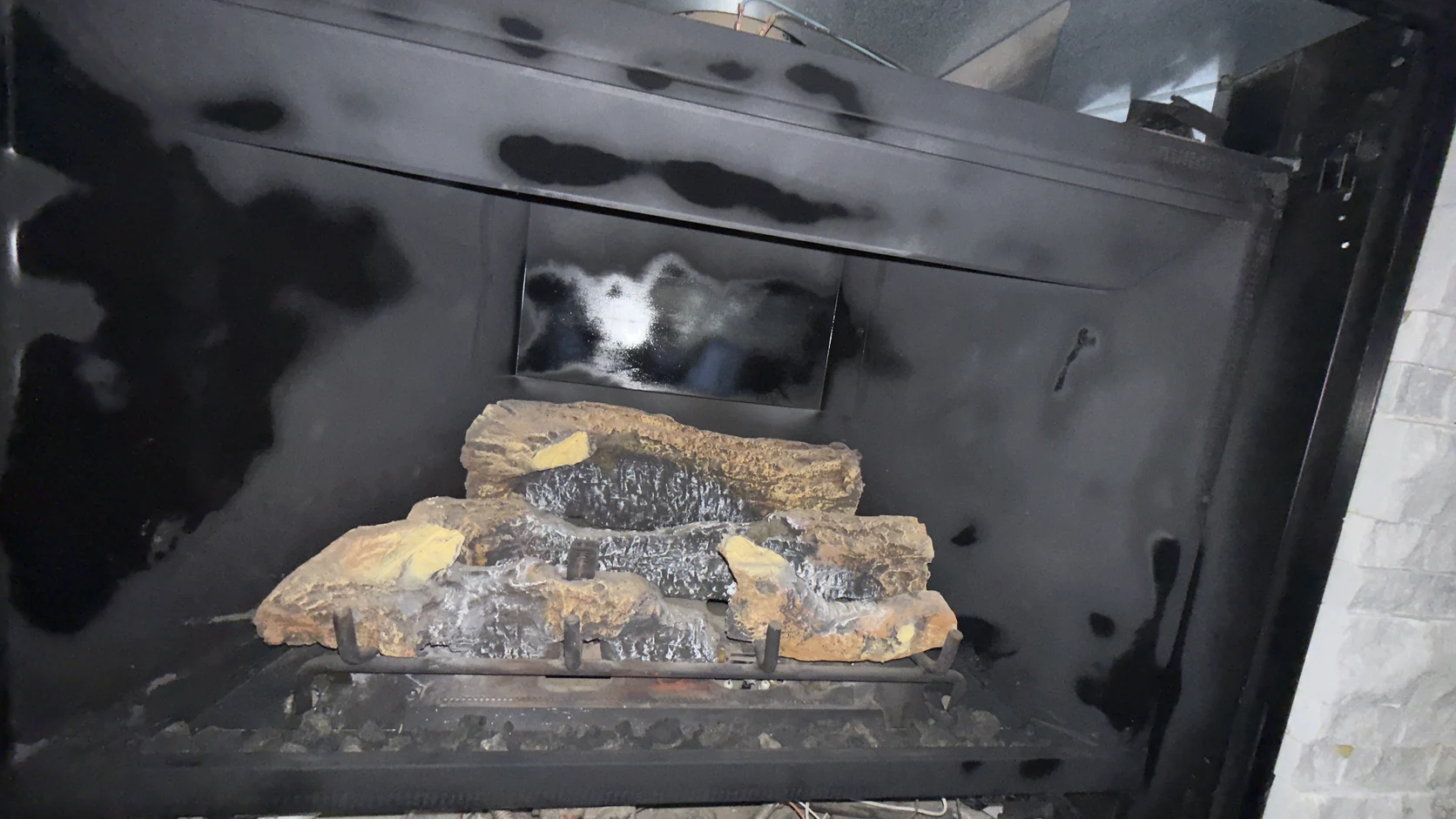 Heavy soot staining inside a firebox with a log set