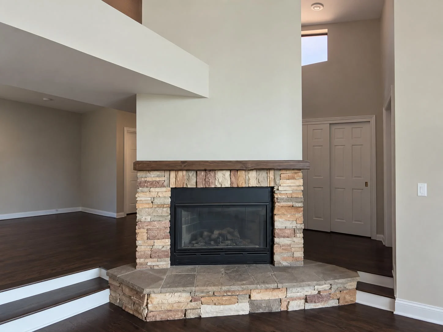 Stacked-stone corner fireplace and hearth in an empty room