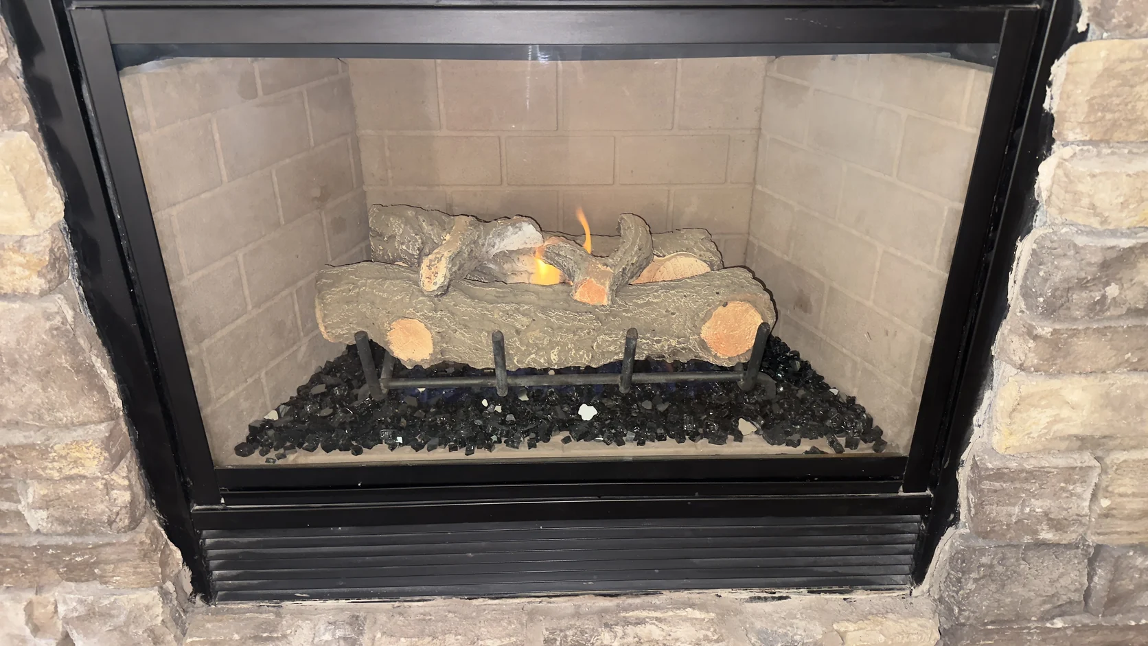 Gas log set in a black firebox with a stone surround