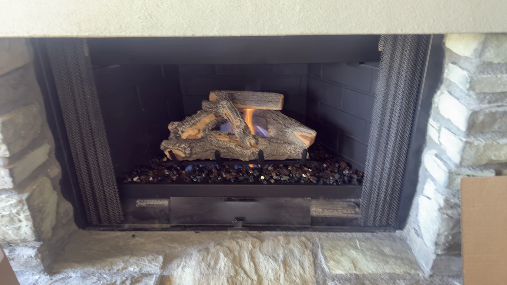 Gas logs in a firebox framed by a stone surround