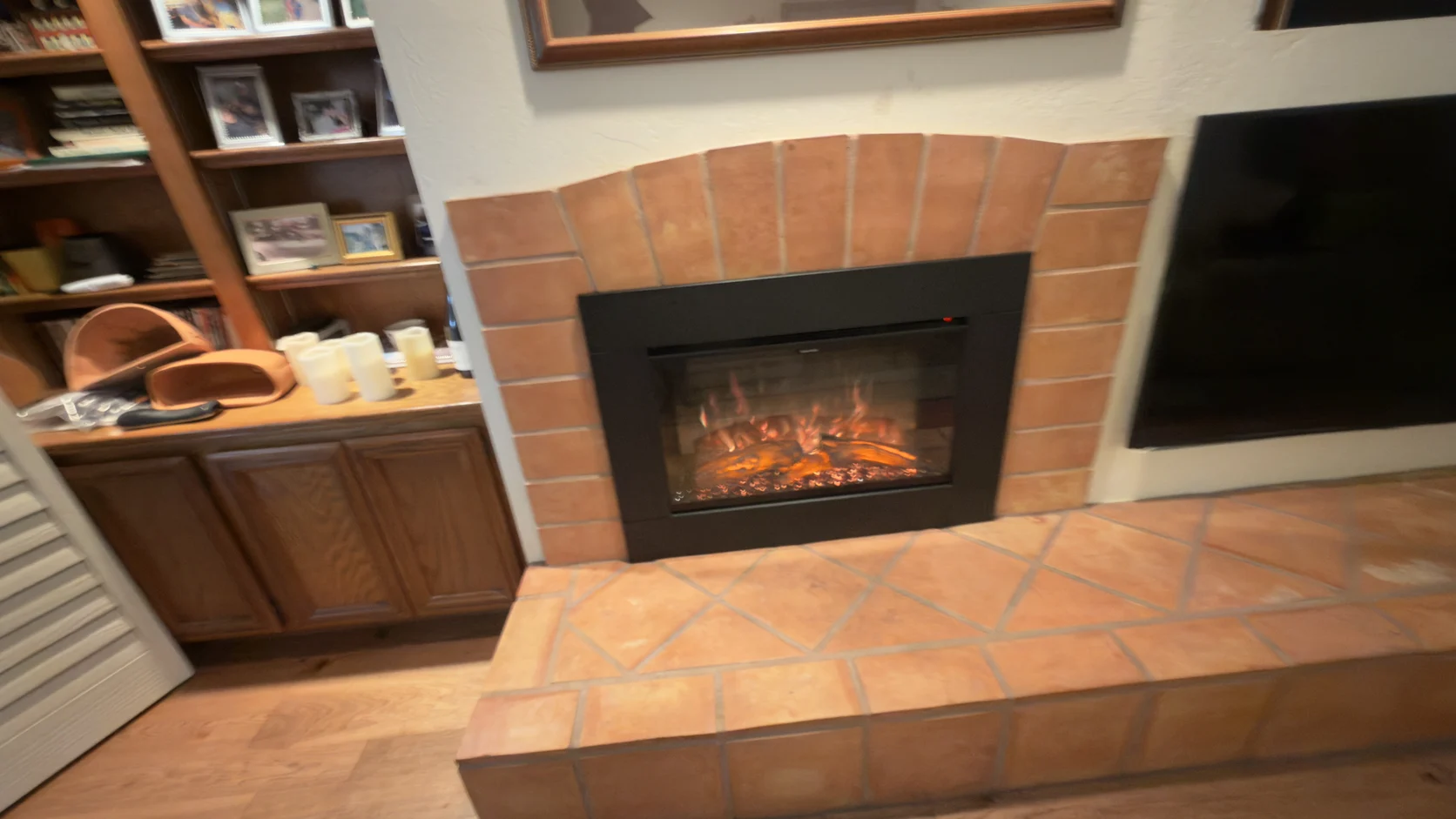 Fireplace insert with a tiled hearth beside kitchen cabinets