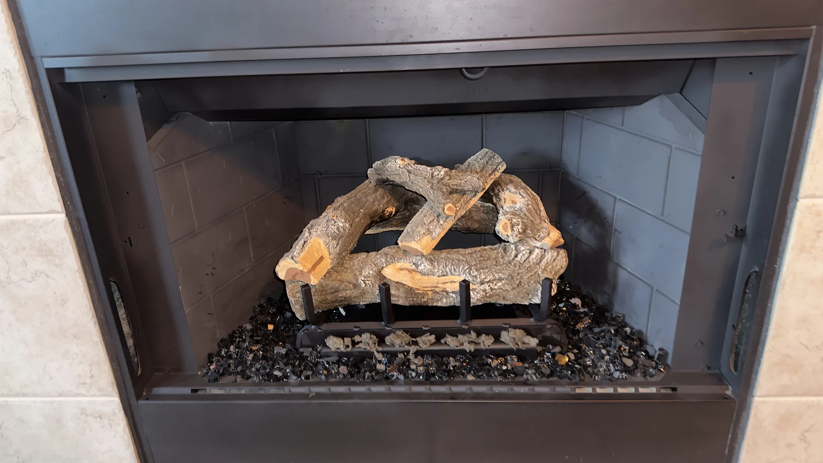 Unlit gas log set in a black metal firebox
