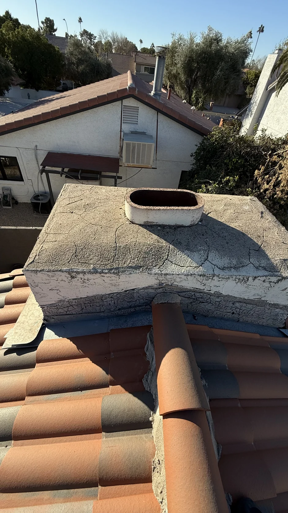Open clay flue at a weathered chimney crown, seen from the roof