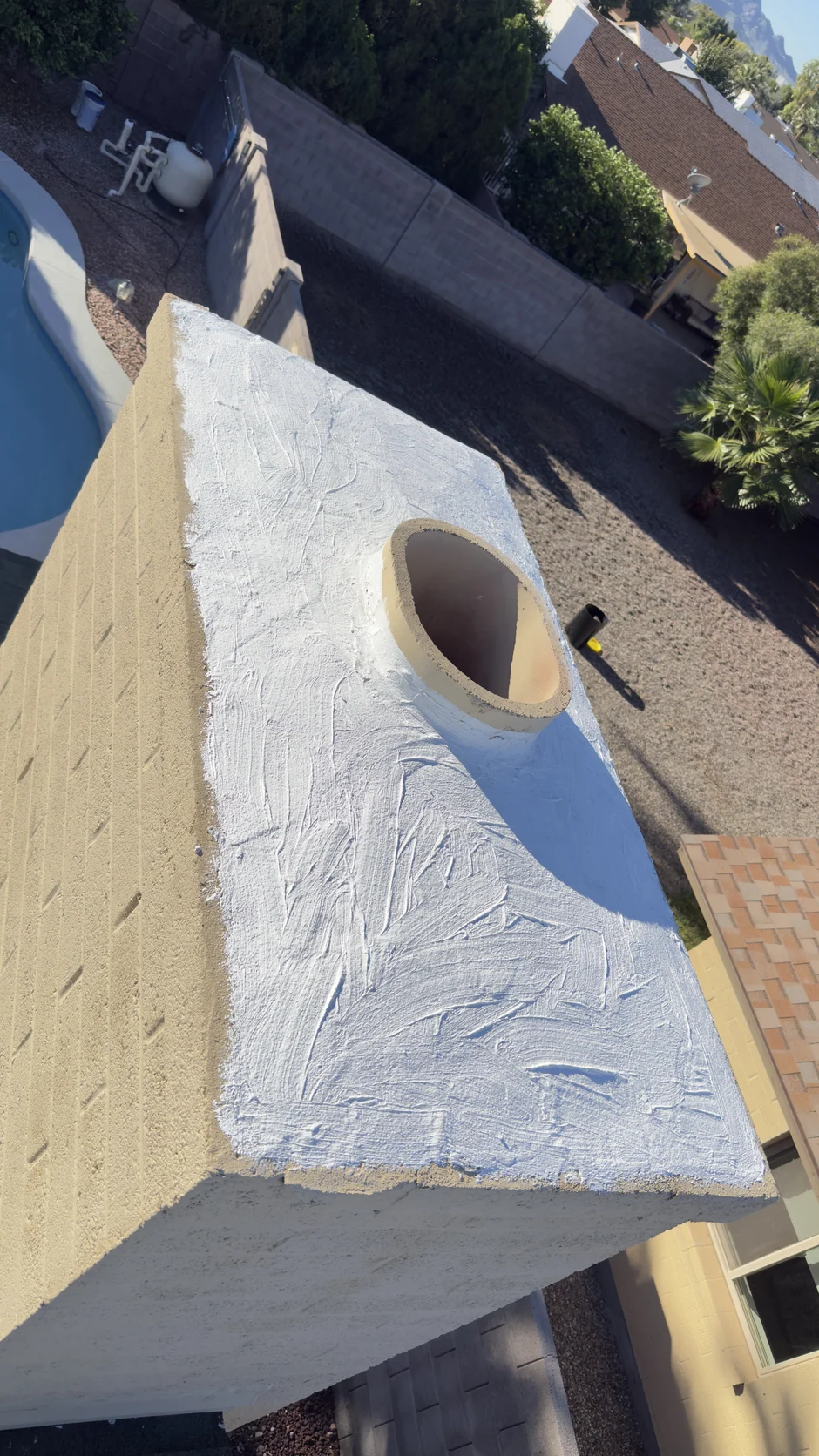Freshly white-coated chimney crown above a tile roof