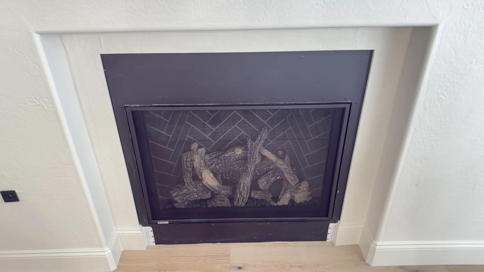 Fireplace insert with a log set in a white mantel